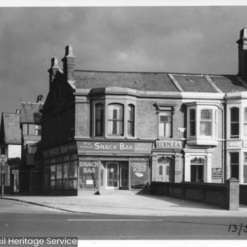 Street corner, with building on the corner advertised as Snack Bar.