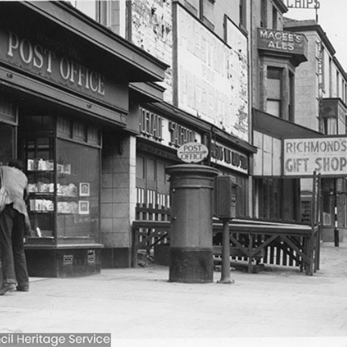 Shop front of the Hounds Hill Post Office with a post box outside.