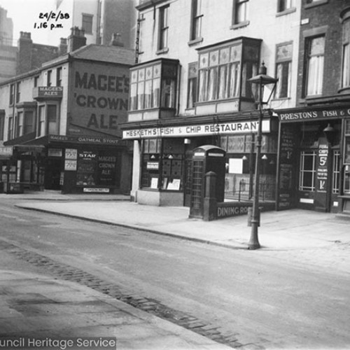 Shop fronts for Preston's Fish and Chip Caterers and Hesketh's Fish and Chip Restaurant. There is also a corner shop with a large advert on the wall for Magee's Crown Ale.