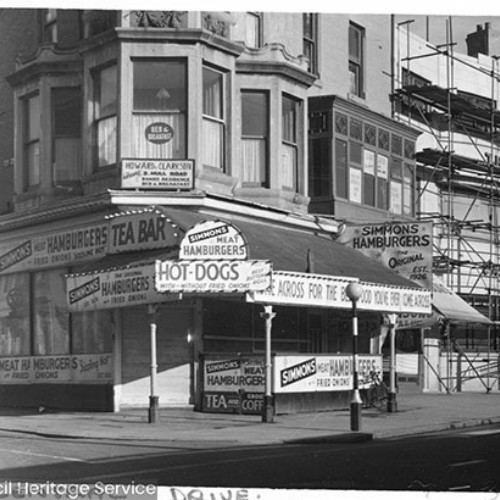 Street corner, with the shop front for Simmons Hamburgers on the ground floor and Howard Clarkson Bed and Breakfast on the upper floor.