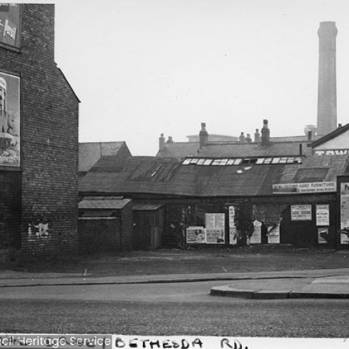 Street corner, with side walls of buildings covered in poster advertisements such as Andrews.