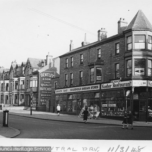 Street corner with Black's Kosher Restaurant on the corner and Bentley and Son Butchers to the left.