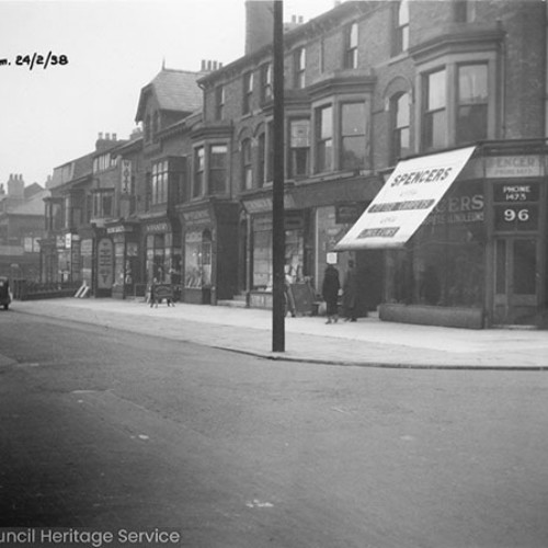 Street corner, with Spencer's House Furnishers shop on the corner and a number of other shop fronts adjoining it to the left.