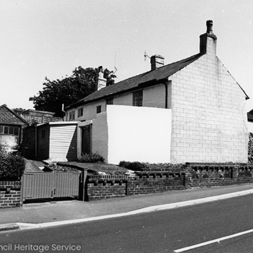 The rear and outbuildings of white-washed cottages.