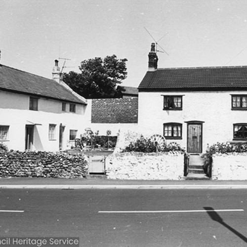 Three smaller white-washed terraced cottages to the left, with one larger white-washed cottage to the right.
