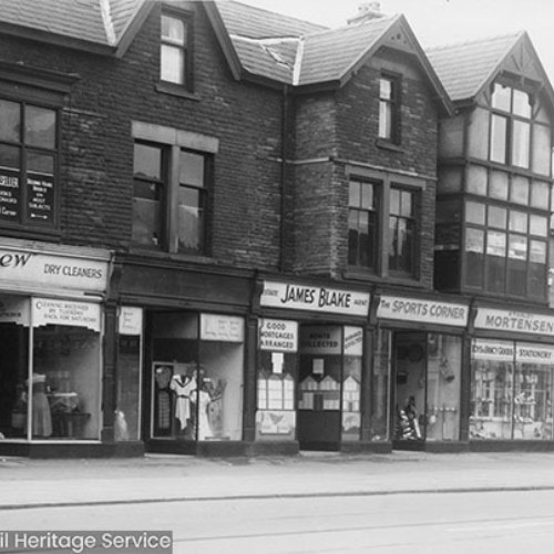 Row of shop fronts, from left to right is Asnew Dry Cleaners, E. Lee, James Blake Estate Agent, The Sports Corner and the Stanley Mortensen shop on the street corner.