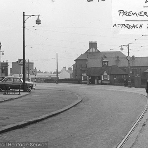 Road bending to the left, with shop fronts on the left hand side.