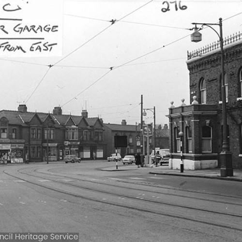 Road bending to the right, with the Oxford Hotel public house on the right and a row of shops on the left.