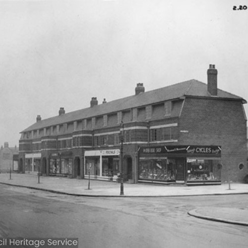 Row of shops, with a bicycle shop at the end on the right.