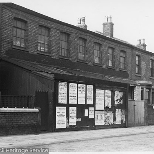 Terraced properties and a wall in the middle covered in advertising posters.