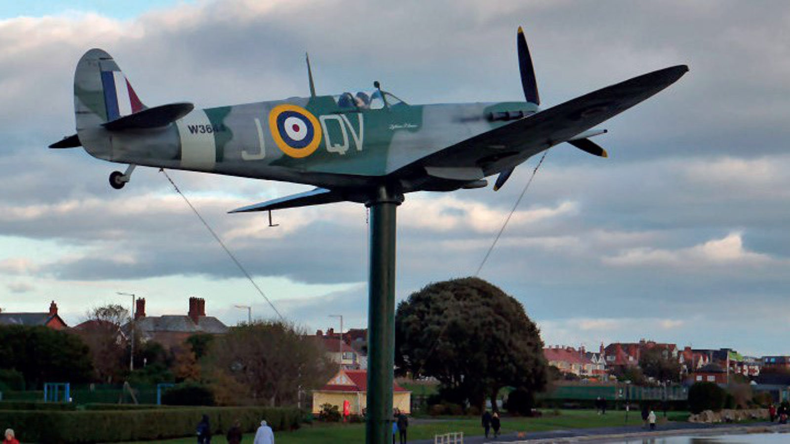 A Spitfire aeroplane mounted on a pole as a memorial in a park.