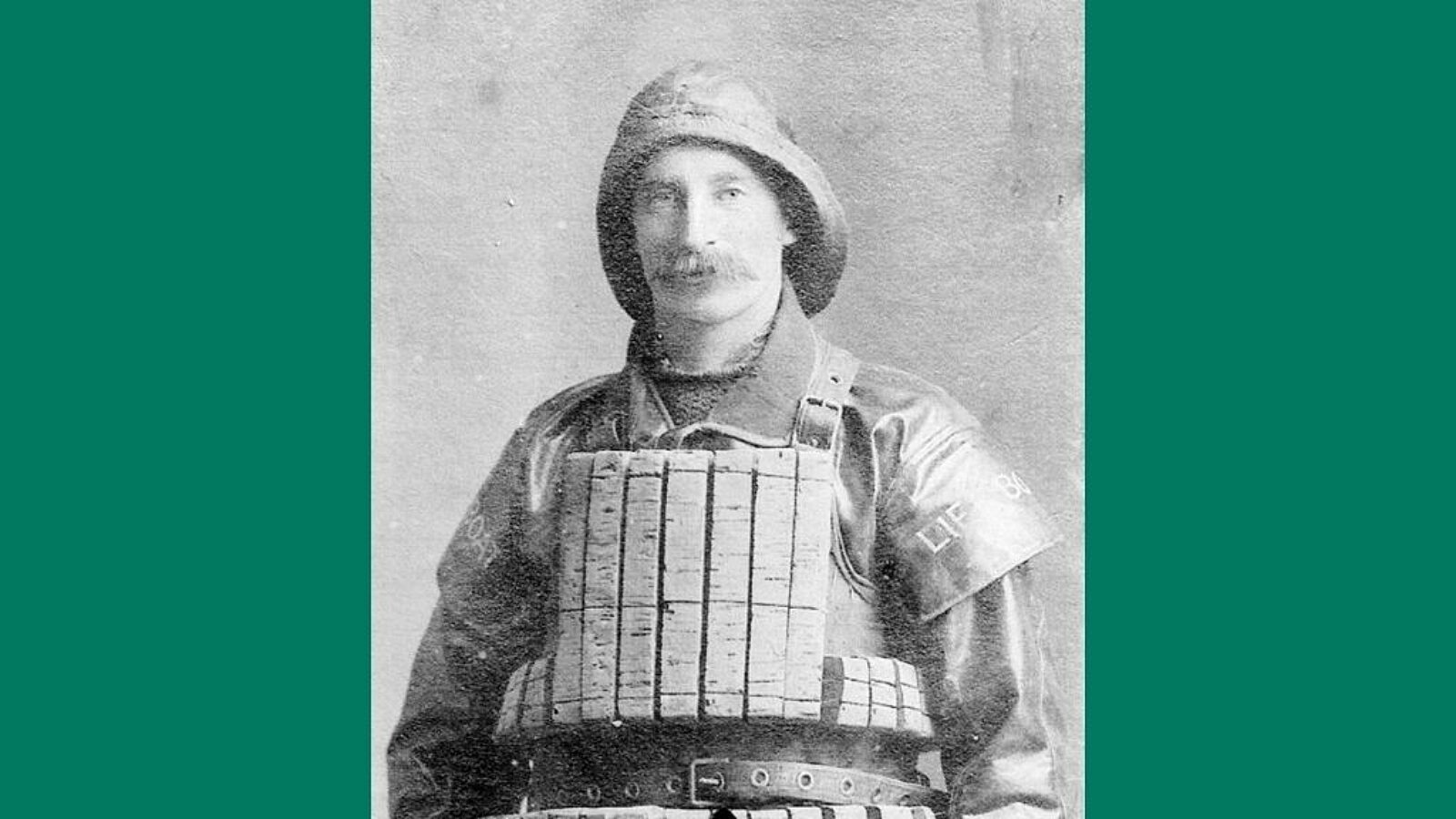A black and white portrait of a man in lifeboat uniform and cork life jacket