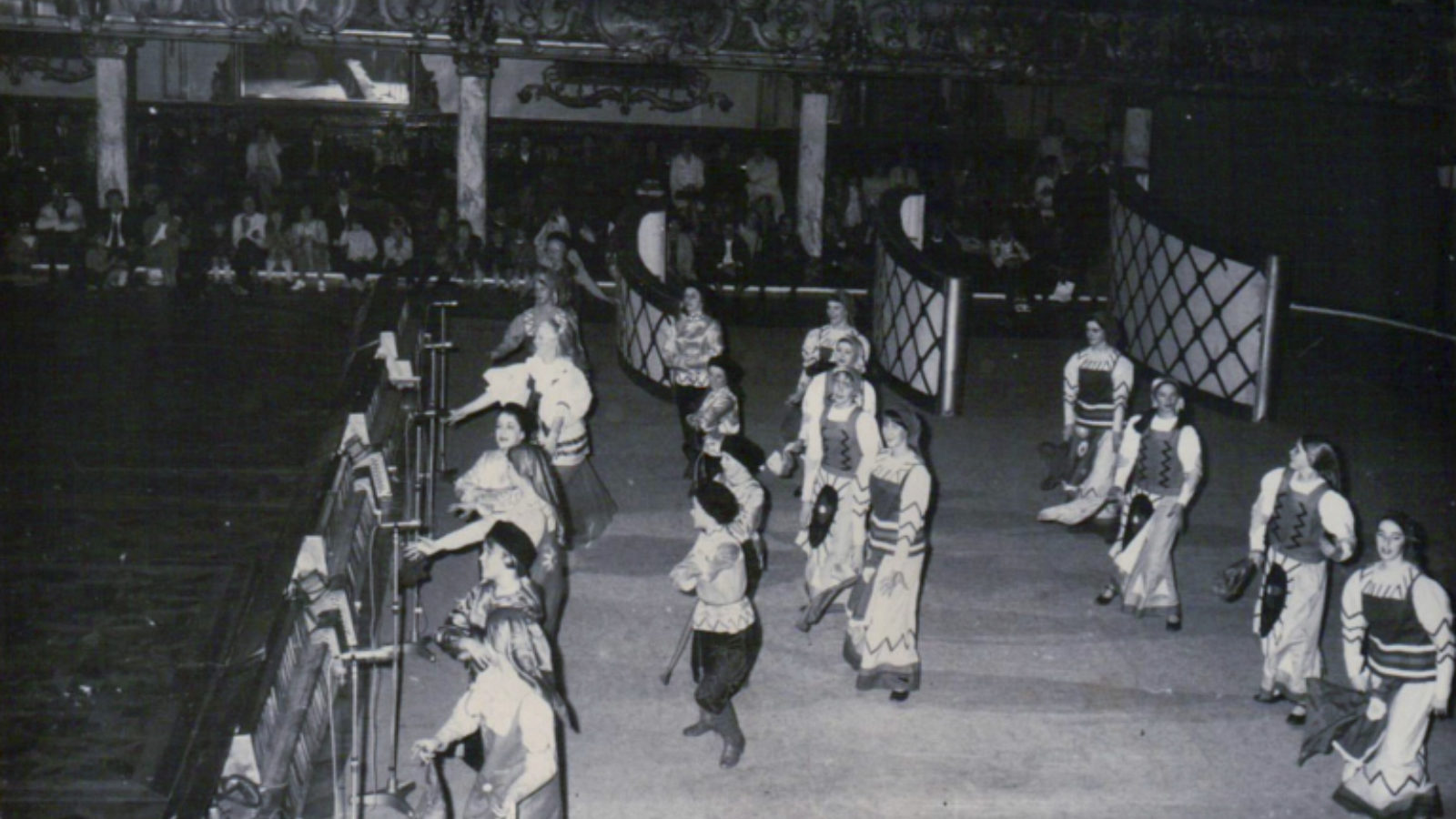 A group of dancers performing on a stage, wearing costumes inspired by traditional Russian clothing.