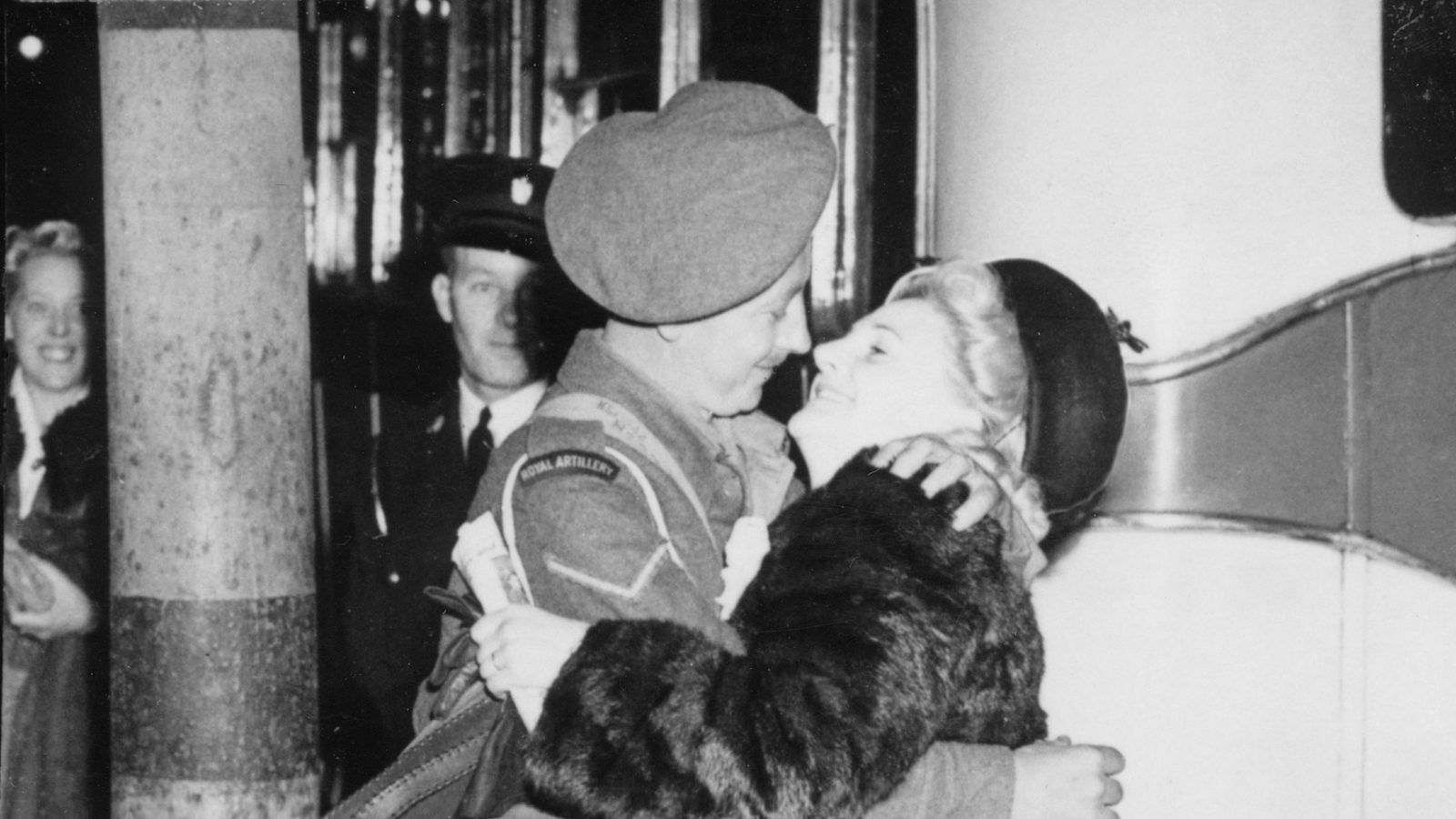 A soldier in uniform embracing a woman