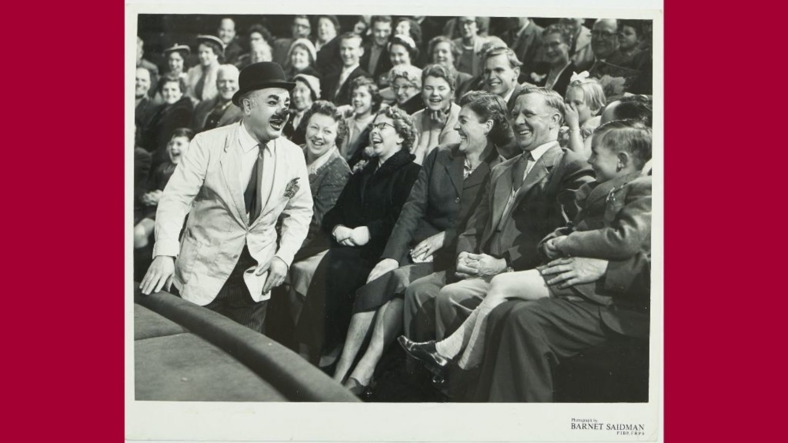 A clown laughs along with the audience in the circus