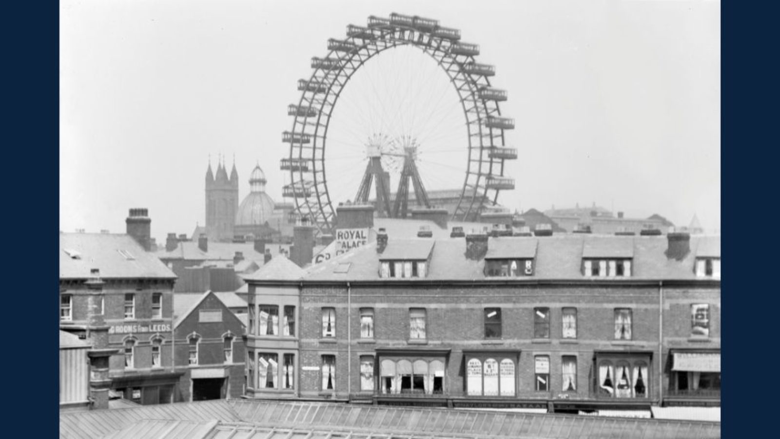 A view across rooftops towards a large Ferris wheel.