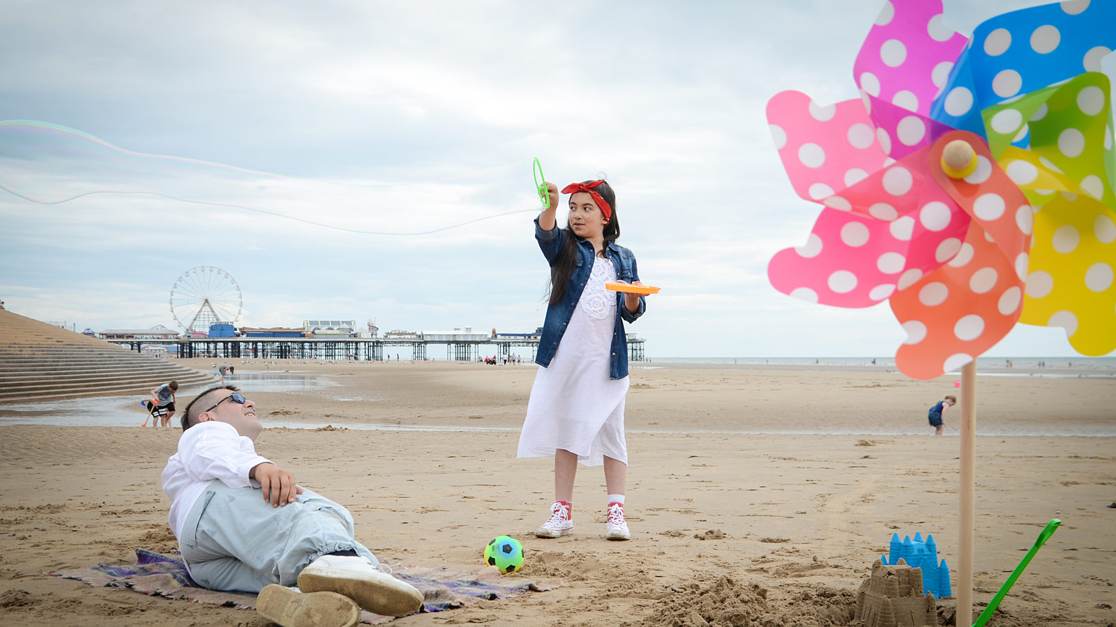 Lady lying and little girl playing with toys on the beach