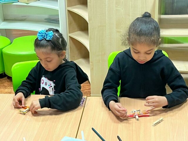 Children sitting around table making their aviation pieces from pegs and lolly sticks