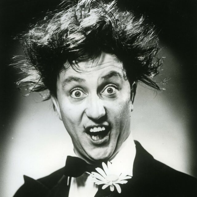 Black and white image of Ken Dodd.  Head and shoulders shot.