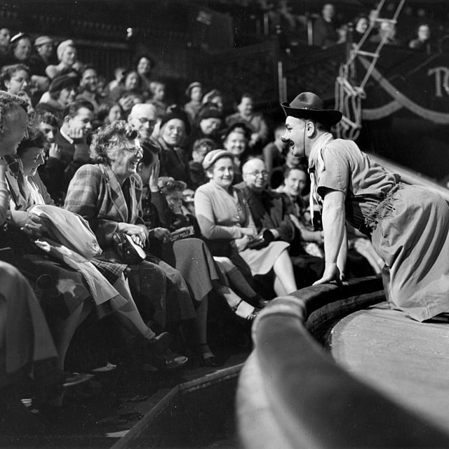 A black and white photograph of Charlie Cairoli leaning into the Tower Circus audience