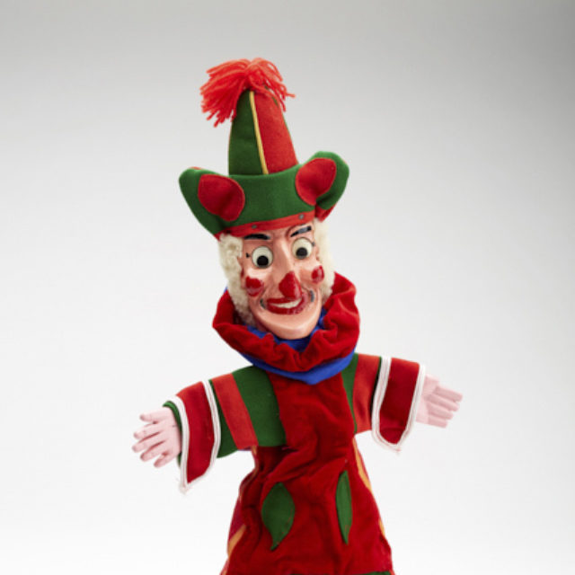 A photograph of a punch puppet, he wears a bright red and green costume