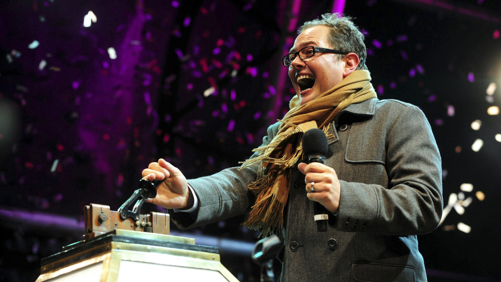 Alan Carr in coat and scarf pulling the illuminations switch on switch