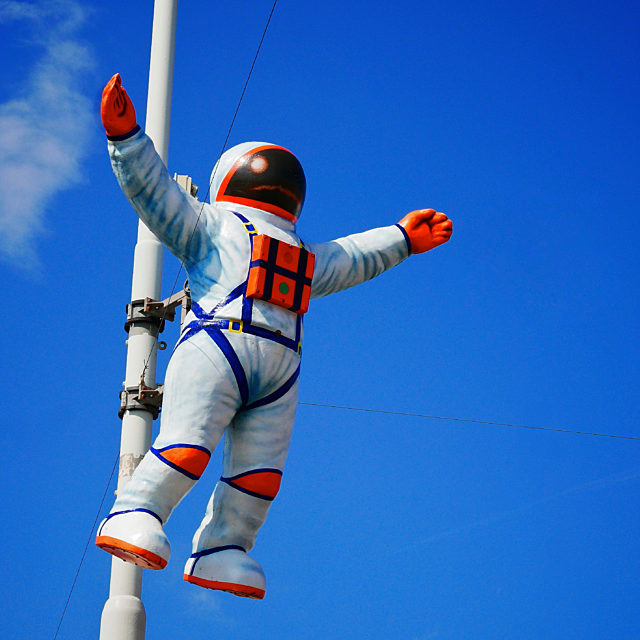 Illuminations spaceman attached to lamppost as if it was flying.  Blue sky background