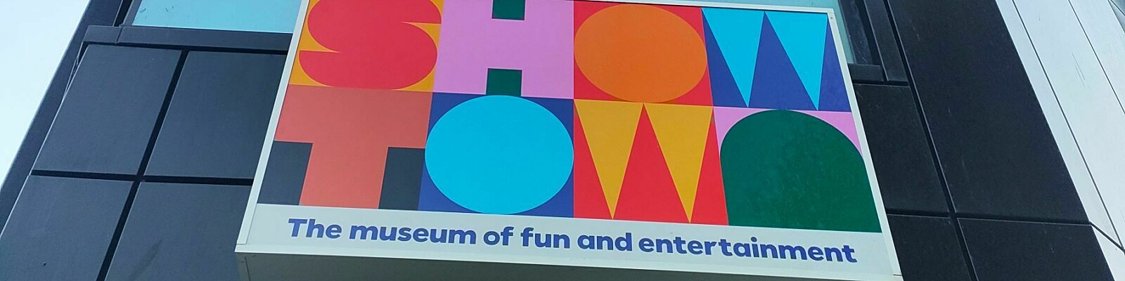 Image of the Showtown sign on the exterior of the museum, a black building with windows.