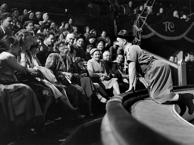Black and white photograph of Charlie Cairoli leaning into the circus audience