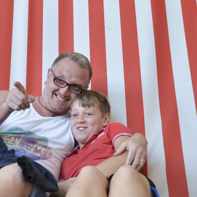 Man and child hugging whilst sat on a stripy deck chair