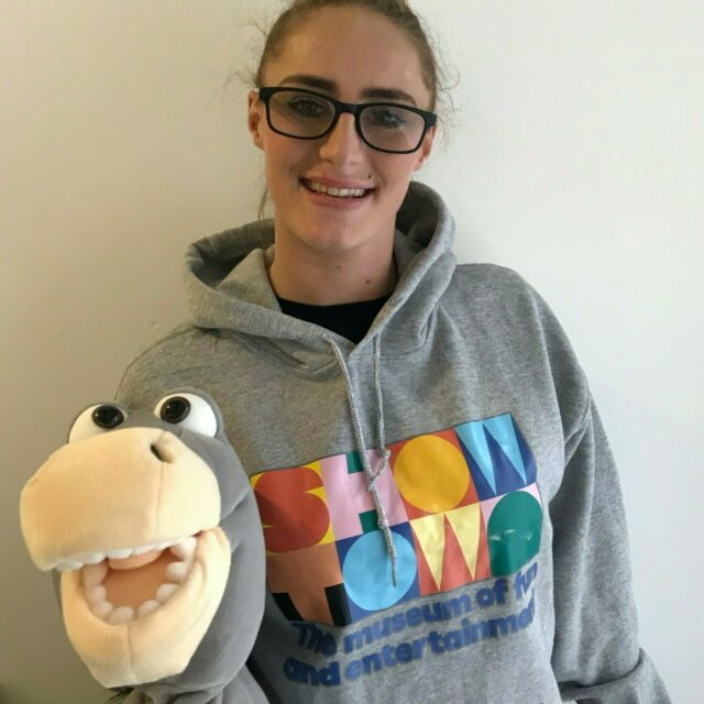 Charley is wearing a Showtown hoody and holding a donkey puppet.