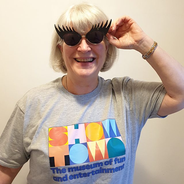 Sue smiling, wearing a Showtown t-shirt and eye lash sunglasses.
