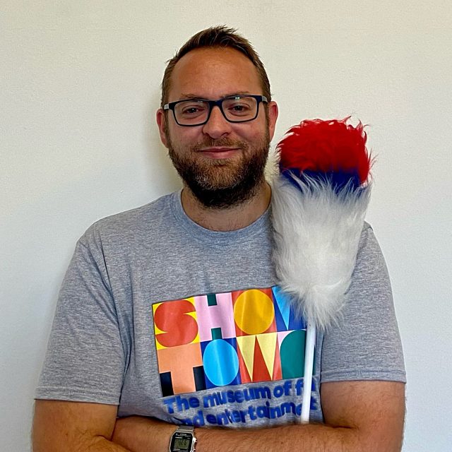 Tom wearing a Showtown t-shirt with a tickle stick.