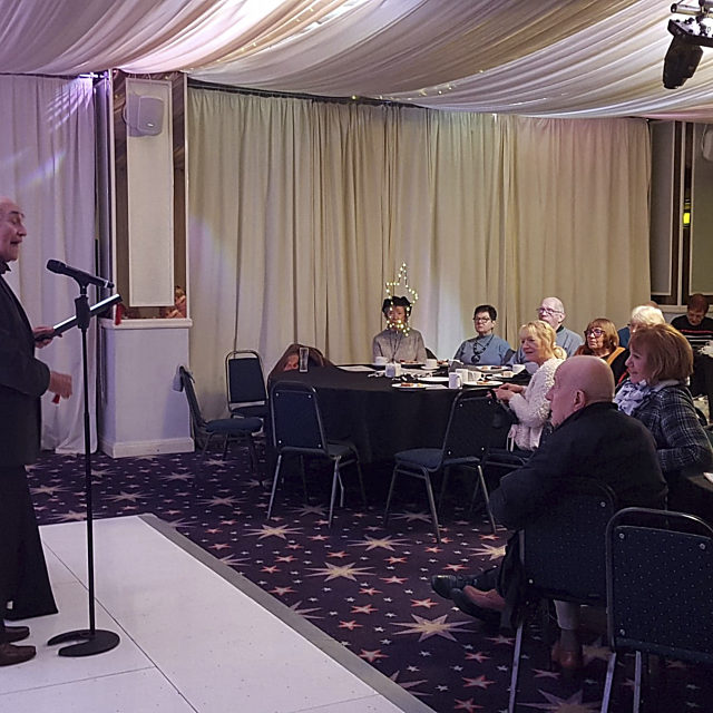 Leslie Melville speaking in front of a smiling crowd
