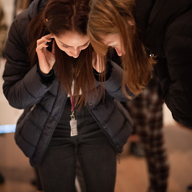 Girls crouched over looking at something out of sight