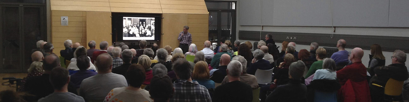 A crowed room filled with people watching a video