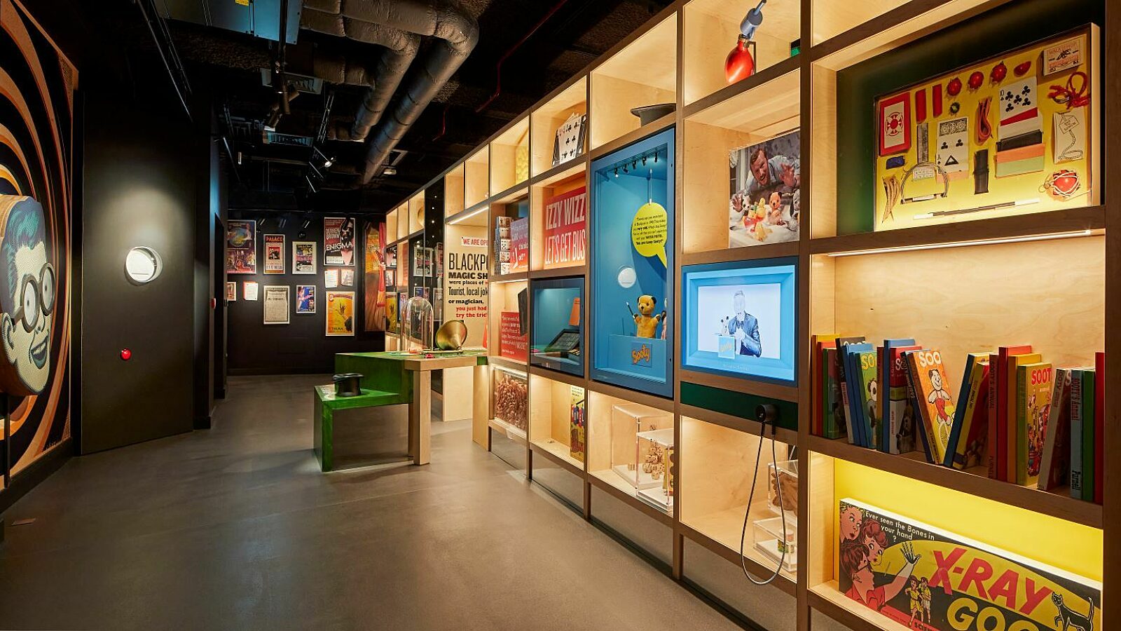 Images shows inside the How's Tricks gallery. Book cases with objects related to magic and joke shops