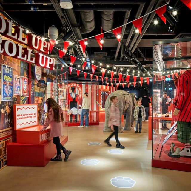 Image of Roll up gallery with family exploring circus related objects including clown and ring master costumes.