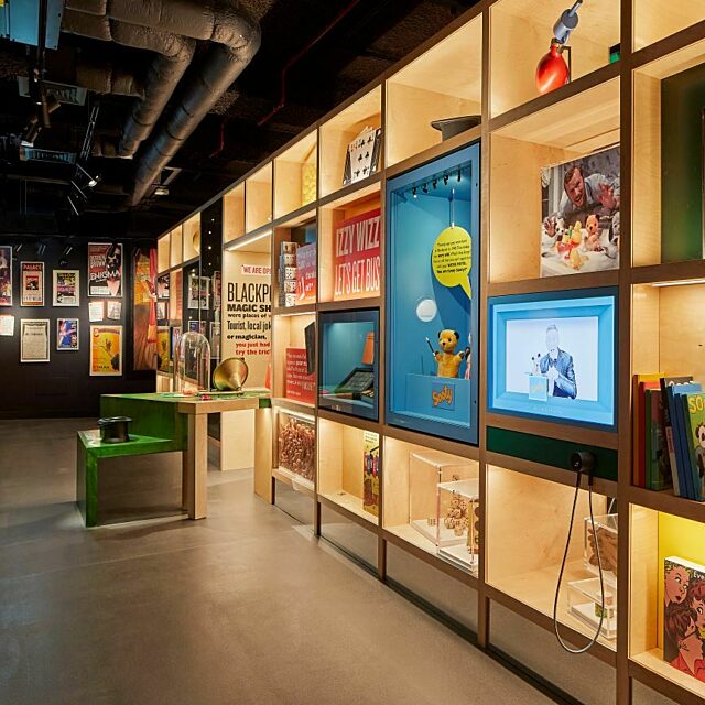 Images shows inside the How's Tricks gallery. Book cases with objects related to magic and joke shops
